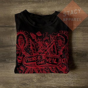 Könnte beinhalten: Schwarzes T-Shirt mit rotem Grafikdesign mit dem Text "PIERCE THE VEIL". Das Design umfasst eine Hand, eine Rakete und geometrische Formen. Das T-Shirt ist von Stacy Apparel.
