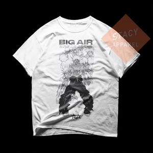 May include: White t-shirt with a black graphic of a person in baggy pants and a crowd of people. The text "BIG AIR" is printed at the top, with additional text below. The shirt is from Stacy Apparel.