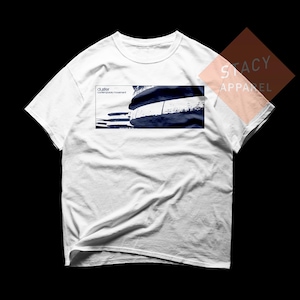 May include: White t-shirt with a rectangular graphic on the front. The graphic features a dark blue and white abstract design with the text "cluster contemporary movement". The shirt is from Stacy Apparel.