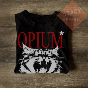 May include: Black t-shirt with a graphic of a snarling cat and the word "OPIUM" in red, with a white asterisk. The shirt is from Stacy Apparel.