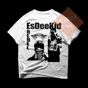 Könnte beinhalten: Weißes T-Shirt mit einem schwarz-weißen Grafikdesign. Das Design enthält den Text "EsDeeKid" und "REBEL" sowie Bilder von zwei Figuren und Wölfen. Der Text "Members only, you won't make it on the guestlist" ist ebenfalls vorhanden.