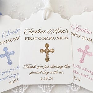 May include: White First Communion tags with scalloped edges, featuring names and dates. Each tag has a cross design and a ribbon. The tags read "First Communion" and "Thank you for sharing this special day with us."