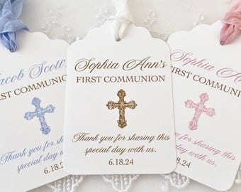 May include: White First Communion tags with scalloped edges, featuring names and dates. Each tag has a cross design and a ribbon. The tags read "First Communion" and "Thank you for sharing this special day with us."