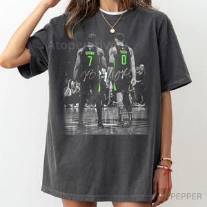 May include: Dark grey t-shirt featuring a black and white image of two basketball players. The players are wearing green and black jerseys with the numbers 7 and 0. The names Brown and Tatum are visible.
