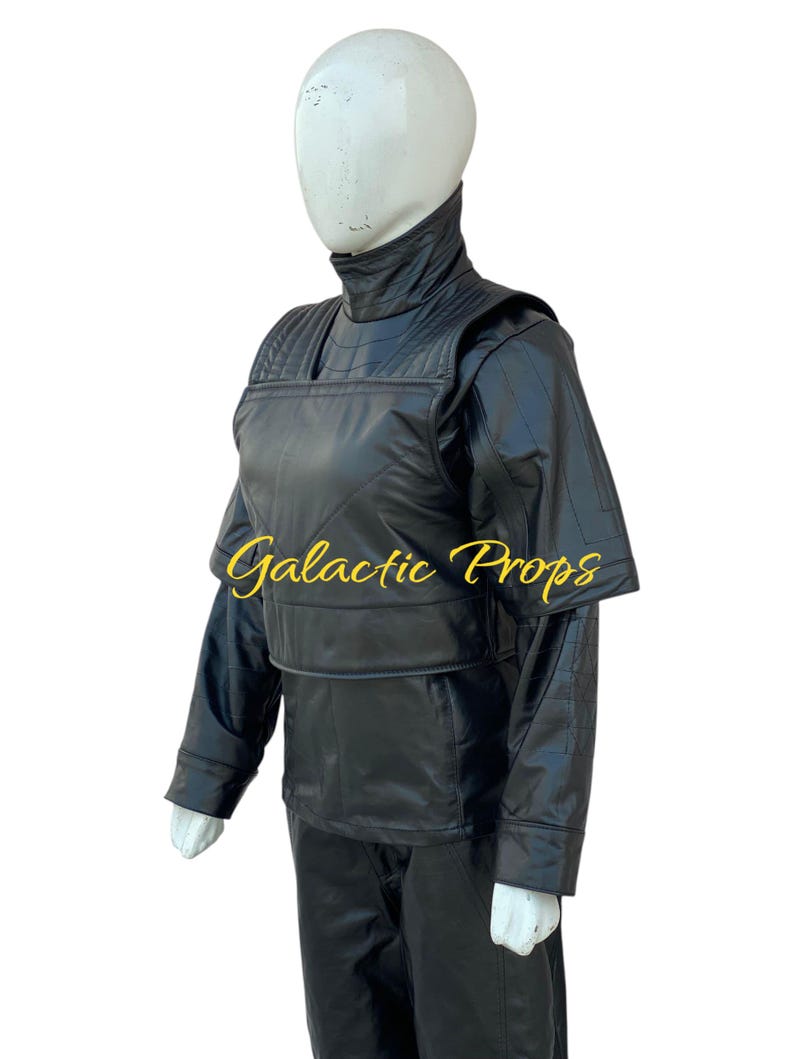 May include: Black costume with a high collar and quilted detailing. The costume includes a jacket with shoulder pads, a vest, and pants. The text "Galactic Props" is printed on the vest. The costume is displayed on a mannequin.