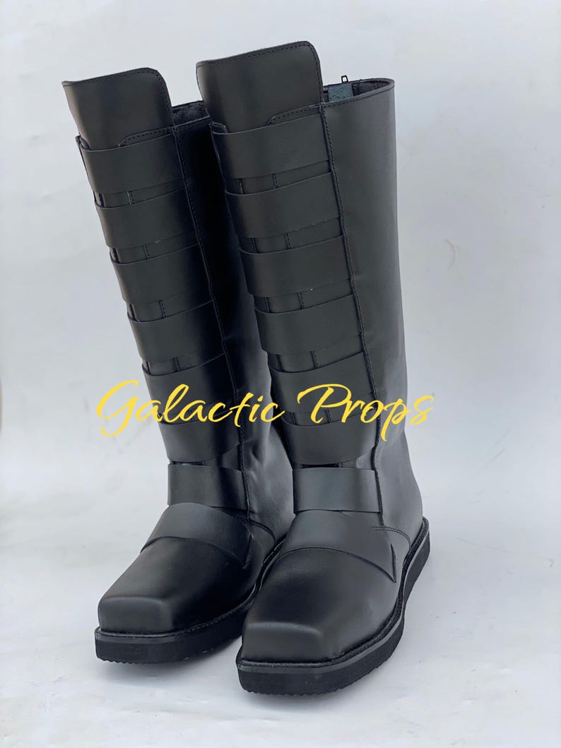 May include: A pair of black knee-high boots with multiple horizontal straps and a square toe. The boots have a flat sole and a zipper on the side. The text "Galactic Props" is visible in the image.