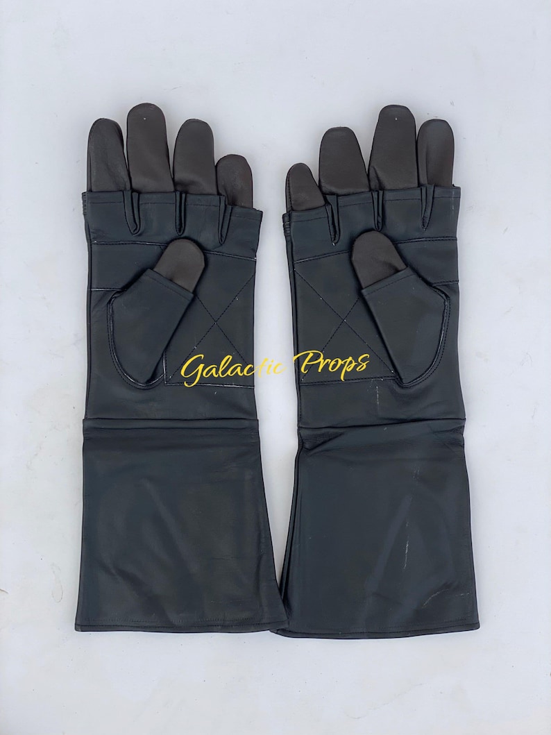 May include: A pair of black leather gloves with extended cuffs. The gloves have a dark grey palm and finger area, with a diamond pattern stitched on the back of the hand. The text "Galactic Props" is visible in gold script.