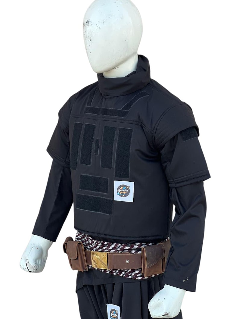 Pu&ograve; includere: Gilet tattico nero con maniche corte, collo alto e toppe rettangolari. Una cintura in pelle marrone con fibbia dorata e due tasche &egrave; indossata in vita. Il logo Galactic Props &egrave; visibile.