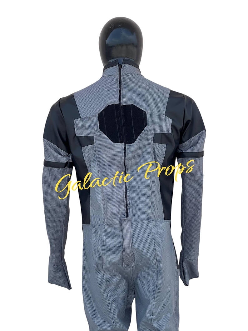 May include: A gray and black jumpsuit with a textured pattern, featuring a central zipper and black accents on the shoulders and chest. The back view of the costume is displayed on a mannequin. The text "Galactic Props" is visible.