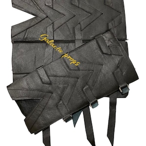 May include: Black leather armor with a chevron pattern and straps. The armor has metal rings and buckles. The text "Galactic Props" is embroidered on the armor in yellow thread.