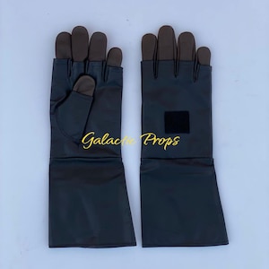 May include: A pair of black gloves with brown fingertips and a long cuff. The gloves have a small black square patch on the cuff. The words "Galactic Props" are written in gold script across the image.