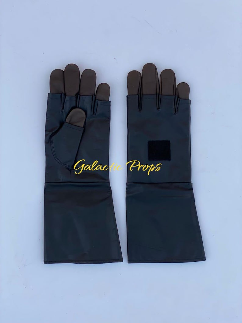 May include: A pair of black gloves with brown fingertips and a long cuff. The gloves have a small black square patch on the cuff. The words "Galactic Props" are written in gold script across the image.