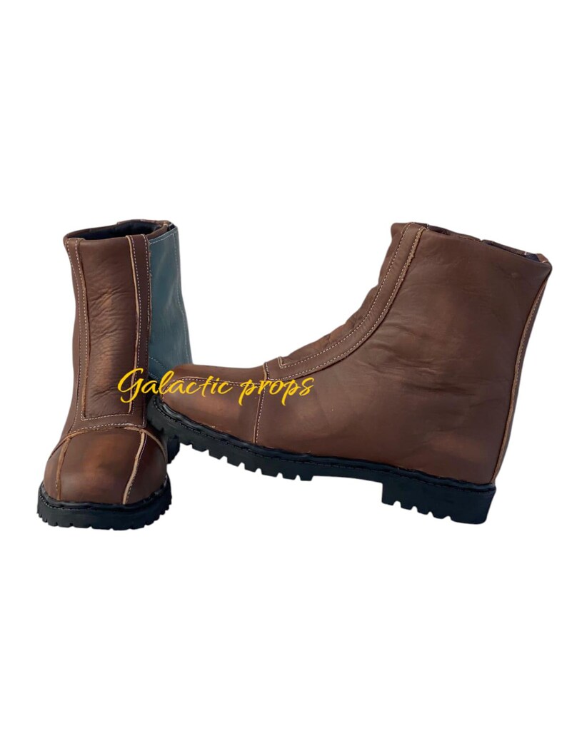 Puede incluir: Un par de botas de cuero marr&oacute;n con una cremallera en el lateral. Las botas tienen una suela de goma negra y una parte superior de cuero marr&oacute;n.