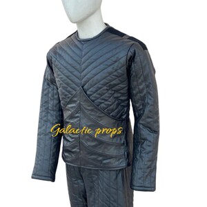 Puede incluir: Mono negro acolchado con un patr&oacute;n de diamante. El mono tiene mangas largas y cuello redondo. El texto "Galactic Props" est&aacute; bordado en la parte delantera del mono.