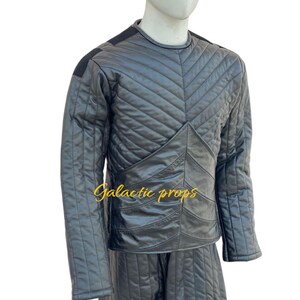 Puede incluir: Un conjunto de chaqueta y pantal&oacute;n acolchados negros con un patr&oacute;n de diamante. La chaqueta tiene un cuello redondo y mangas largas. El pantal&oacute;n tiene una pierna recta. El texto "Galactic Props" es visible en la parte delantera de la chaqueta.