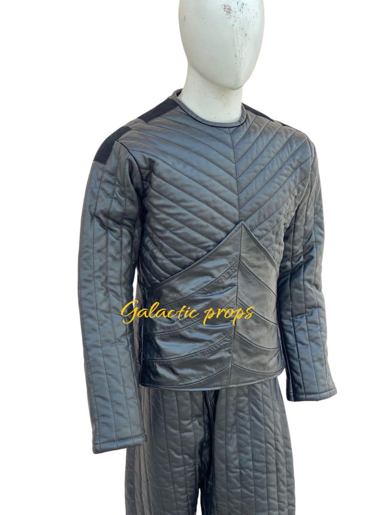 Puede incluir: Un conjunto de chaqueta y pantal&oacute;n acolchados negros con un patr&oacute;n de diamante. La chaqueta tiene un cuello redondo y mangas largas. El pantal&oacute;n tiene una pierna recta. El texto "Galactic Props" es visible en la parte delantera de la chaqueta.