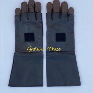 May include: A pair of black gloves with brown fingertips and a black square patch on the wrist area. The gloves have long sleeves and the text "Galactic Props" is visible in gold.