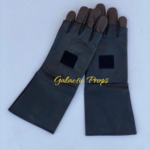 May include: A pair of black gloves with brown fingertips and long cuffs. Each glove has a small black square patch near the wrist. The text "Galactic Props" is in gold script across the image.