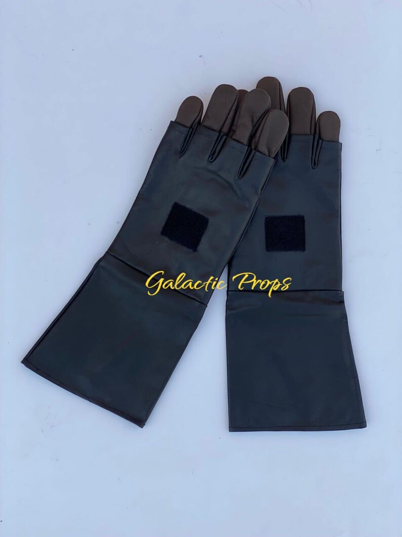 May include: A pair of black gloves with brown fingertips and long cuffs. Each glove has a small black square patch near the wrist. The text "Galactic Props" is in gold script across the image.