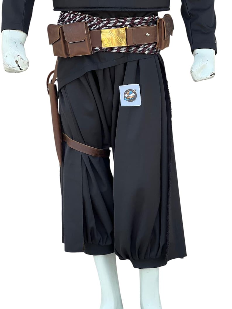 Pu&ograve; includere: Pantaloni neri da costume con caviglia arricciata e fondina in pelle marrone. Una cintura marrone e dorata con fibbia dorata &egrave; indossata in vita. Il testo "Galactic Props" &egrave; su un piccolo adesivo sui pantaloni.