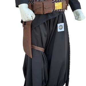 Pu&ograve; includere: Un costume nero con tasche in pelle marrone e una cintura con fibbia dorata. Il costume comprende un top nero, pantaloni e una fondina in pelle marrone. Il costume ha una toppa Galactic Empire.