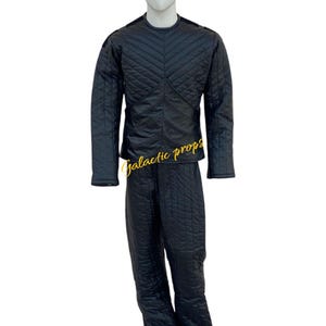 Puede incluir: Un mono negro acolchado con un patr&oacute;n de diamante. El mono tiene mangas largas y un cuello alto.