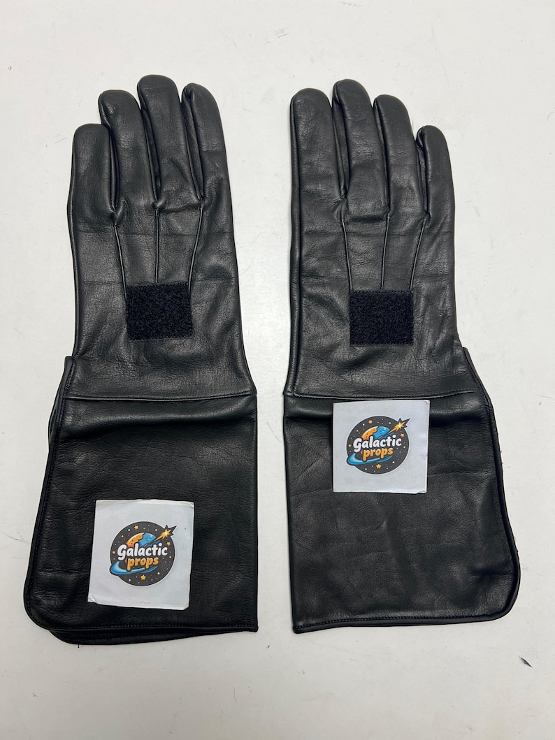 May include: A pair of black leather gloves with extended cuffs. Each glove has a rectangular velcro patch on the back of the hand and a white sticker with the text "Galactic Props".