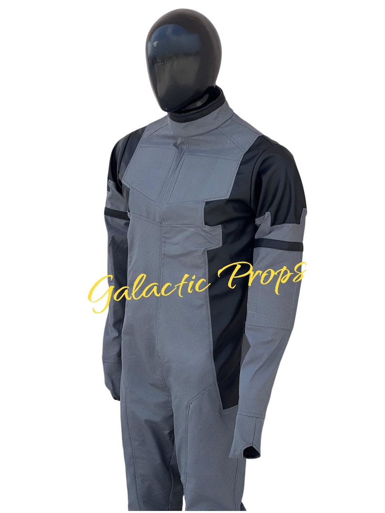 May include: A gray and black jumpsuit with the text "Galactic Props" in a gold script. The jumpsuit has a high collar, long sleeves, and a textured pattern on the front and sleeves. The mannequin head is black.