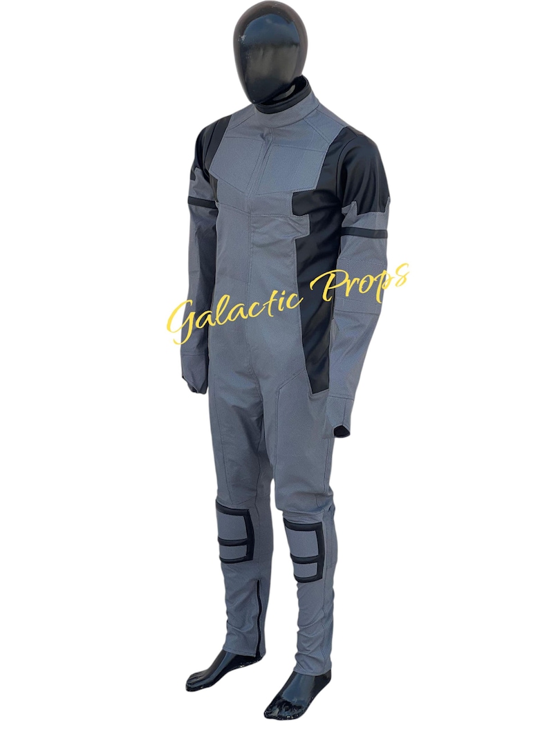 May include: A gray and black jumpsuit with the text "Galactic Props". The jumpsuit features a high collar, long sleeves, and reinforced knee pads. The mannequin is wearing black boots.