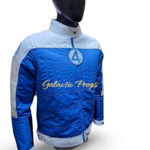 May include: Blue and white jacket with a round collar and a circular patch featuring a stylized number 4. The jacket has a quilted design on the blue sections and the text "Galactic Props" in gold lettering.