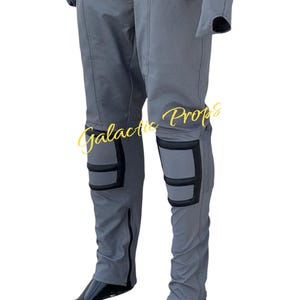 May include: Gray jumpsuit with black accents, featuring knee pads and zippers. The text "Galactic Props" is visible in a gold script. The jumpsuit appears to be made of a textured fabric, possibly for a costume or cosplay.