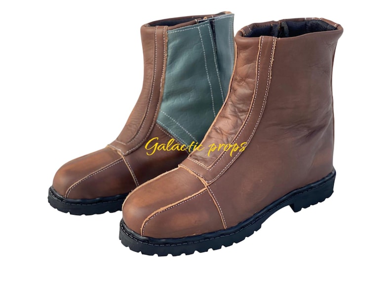 Puede incluir: Un par de botas de cuero marr&oacute;n con una cremallera en la parte posterior. Una bota tiene un panel de tela verde en la parte posterior. Las botas tienen una suela de goma gruesa.