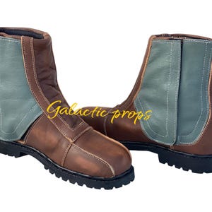 Puede incluir: Un par de botas de cuero marr&oacute;n con un panel de gamuza verde en el lateral. Las botas tienen un cierre de cordones en la parte delantera y un tac&oacute;n grueso.