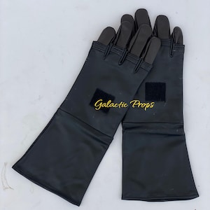May include: A pair of black gloves with long cuffs. The gloves have a smooth, shiny texture and feature a small square patch on each cuff. The fingers are segmented and reinforced. The text "Galactic Props" is visible in the image.