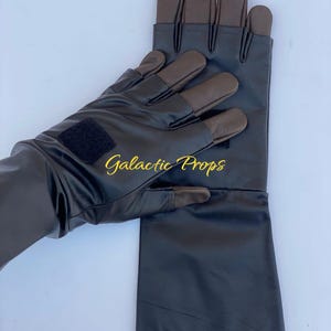 May include: Black gloves with brown fingertips and a black velcro patch. The gloves have a long cuff and the text "Galactic Props" in gold lettering.