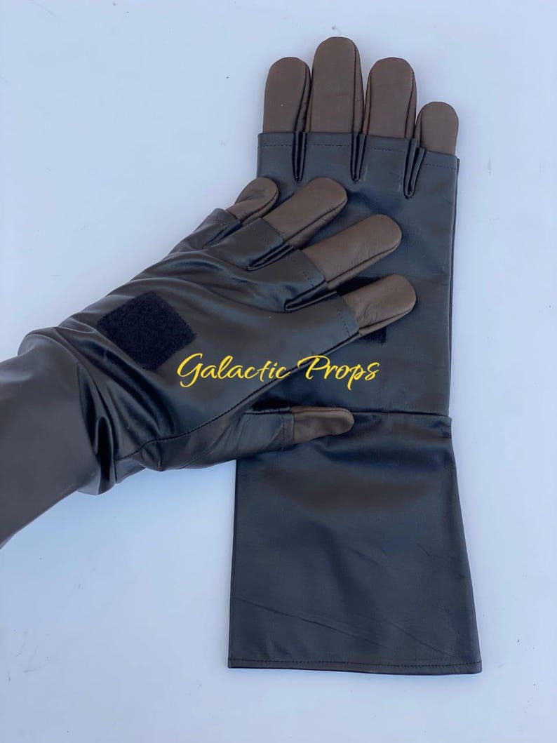 May include: Black gloves with brown fingertips and a black velcro patch. The gloves have a long cuff and the text "Galactic Props" in gold lettering.