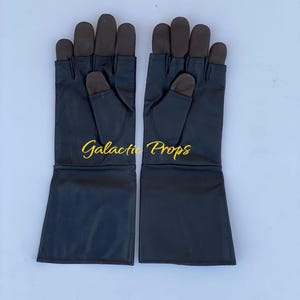 May include: A pair of black gloves with brown fingertips and the text "Galactic Props" in gold lettering. The gloves have long cuffs and are displayed on a light blue background.