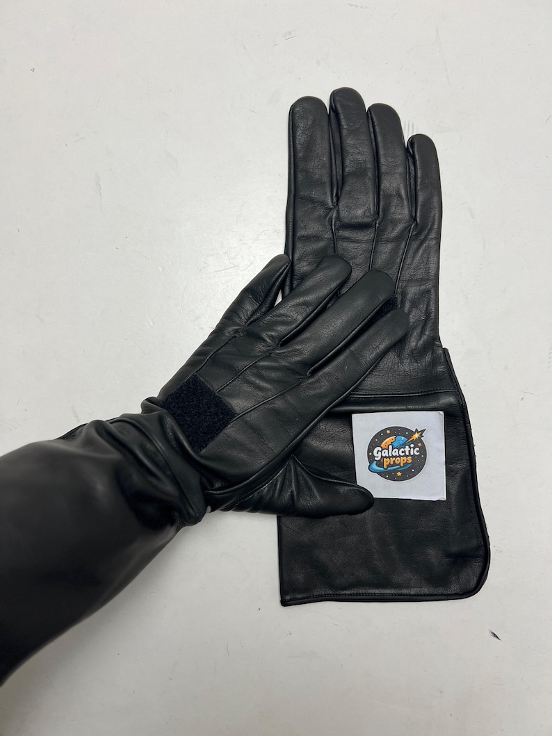 May include: Black leather gloves with extended cuffs. One glove features a Velcro strap at the wrist. A white label with the text "Galactic Props" is attached to the cuff of one glove.