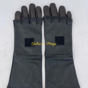May include: A pair of black gloves with long cuffs, featuring a rectangular black patch on each. The gloves have a segmented design on the fingers and are likely made of a synthetic material. The text "Galactic Props" is visible.