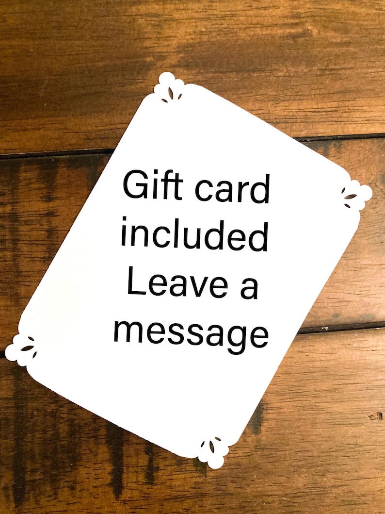 May include: White gift card with decorative corner cutouts. The card includes the text "Gift card included Leave a message" in black font. The card is set against a wooden background.