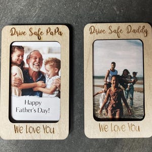 May include: Two wooden photo frames with a white background and a photo insert. The top frame says "Drive Safe PaPa" and the bottom frame says "Drive Safe Daddy". Both frames have the text "We Love You" at the bottom and a message inside the photo insert. The left frame says "Happy Father's Day!" and the right frame has a photo of a family.
