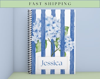 Könnte beinhalten: Ein spiralgebundenes Notizbuch mit blau-weiß gestreiftem Einband. Der Einband zeigt eine Aquarellillustration von blauen Hortensien und den Namen "Jessica" in einem weißen Rechteck. Der Text "FAST SHIPPING" steht oben.