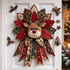 May include: A quilted fabric wall hanging featuring a central reindeer head with antlers, surrounded by layered leaf-shaped fabric petals in red, green, and brown patterns. The piece includes holly accents and hanging ornaments shaped like stars and a tree.
