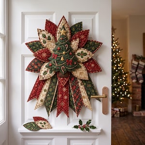 May include: A quilted fabric wall hanging shaped like a large poinsettia flower with a central Christmas tree ornament. The design features red, green, and cream fabric panels with star, holly, and plaid patterns. Two loose fabric leaves sit below.