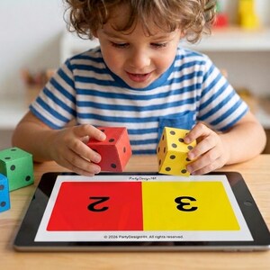 May include: A child is playing with colorful dice and a tablet. The dice are red, yellow, green, and blue, each with black dots. The tablet displays the numbers 2 and 3 on red and yellow backgrounds, respectively. Educational toy.