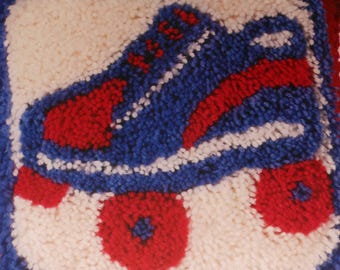 Könnte beinhalten: Ein Nahaufnahme eines blauen und roten Rollschuh-Teppichs. Der Teppich ist aus Garn gefertigt und hat einen weißen Hintergrund.