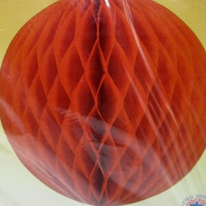 May include: A red honeycomb paper ball decoration, completely assembled and ready to hang. The ball is made of tissue paper and has a delicate, intricate design. It is a popular choice for parties and celebrations.