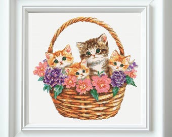 May include: Four kittens sit in a woven wicker basket with a brown handle. The basket is filled with pink, purple, and white flowers. The kittens are looking at the camera. The kittens are brown, orange, and white.