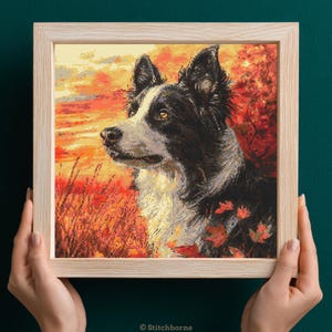 May include: A framed cross-stitch of a Border Collie dog in a fall landscape. The dog is black and white, with a detailed stitch pattern. The background features orange and red foliage, and a sunset sky. The frame is light wood.