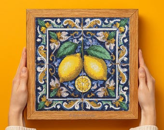 May include: A framed artwork with a lemon design. The artwork is made of four square tiles with a blue and white floral pattern. Two yellow lemons and a lemon slice are shown, with green leaves. The frame is made of light brown wood.